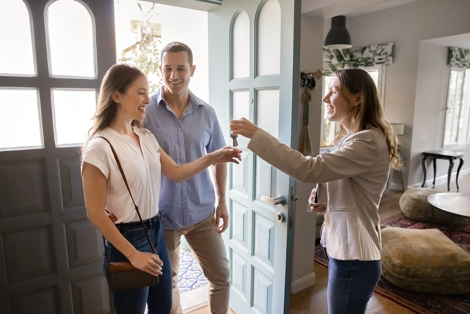 Realtor agent handing house keys to happy couple in doorway